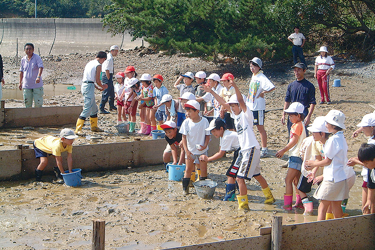 地域小学校の児童により、干潟実験区にアサリを放流